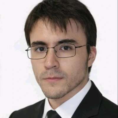 Retrato de Diego Brito, con lentes y traje oscuro.